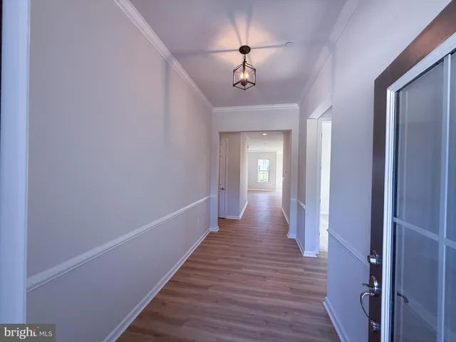 a view of a hallway with wooden floor and chandelier