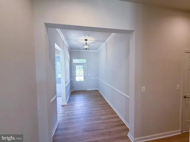a view of a hallway with wooden floor and chandelier