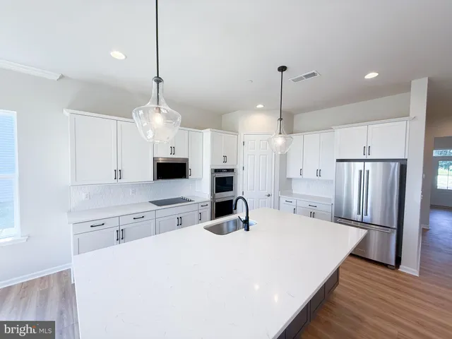a large kitchen with kitchen island a stove a sink a center island a refrigerator and a wooden floor
