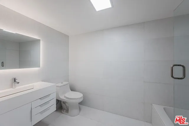 a bathroom with a granite countertop shower a toilet and sink