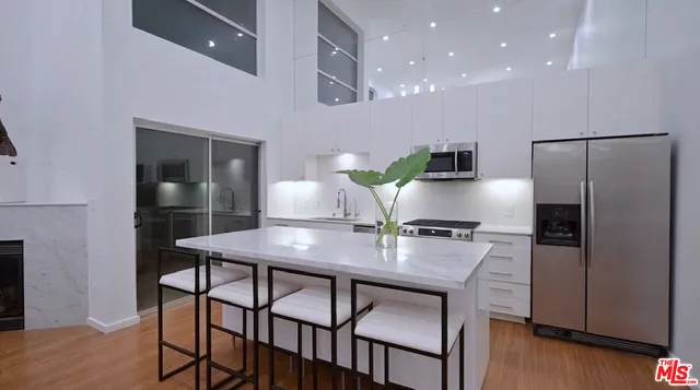 a kitchen with stainless steel appliances granite countertop a kitchen island a table and chairs in it