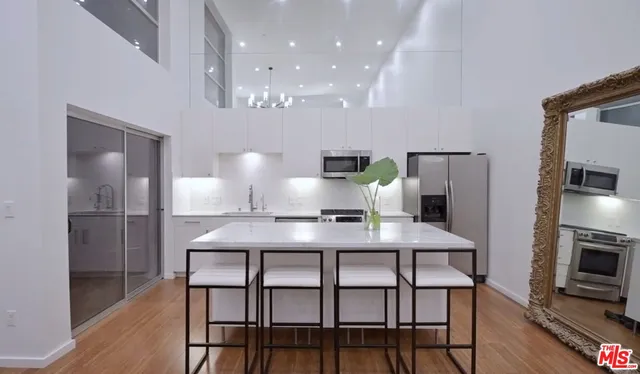 a kitchen with stainless steel appliances a table chairs refrigerator and microwave