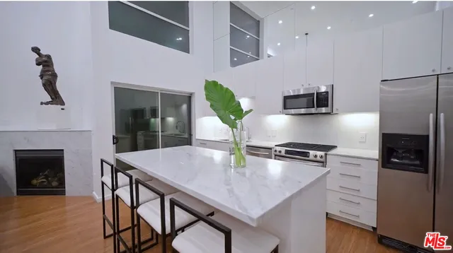 a kitchen with stainless steel appliances a dining table chairs stove and refrigerator