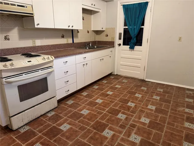 a kitchen with granite countertop a stove a sink and a white cabinets
