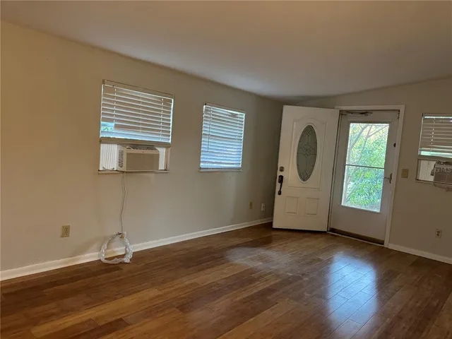 a view of an empty room with wooden floor and a window