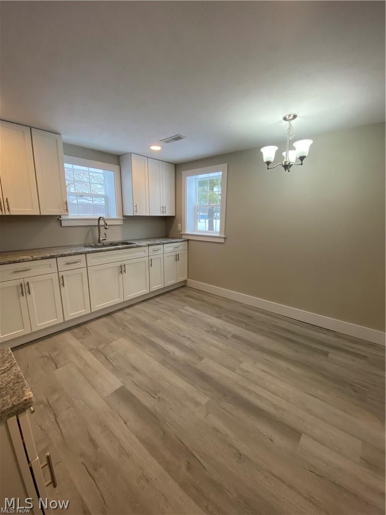 2803 State Road Vermilion, OH 44089 - Photo 13 of 28 Kitchen with brand new white cabinets, light wood finished floors, hanging light fixture, and granite counter tops.