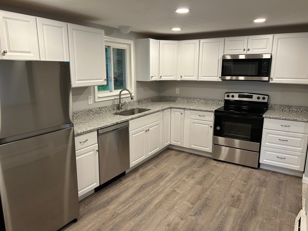 73 Brooks Street Maynard, MA 01754 - Photo 4 of 17 a kitchen with a sink a microwave a refrigerator and cabinets