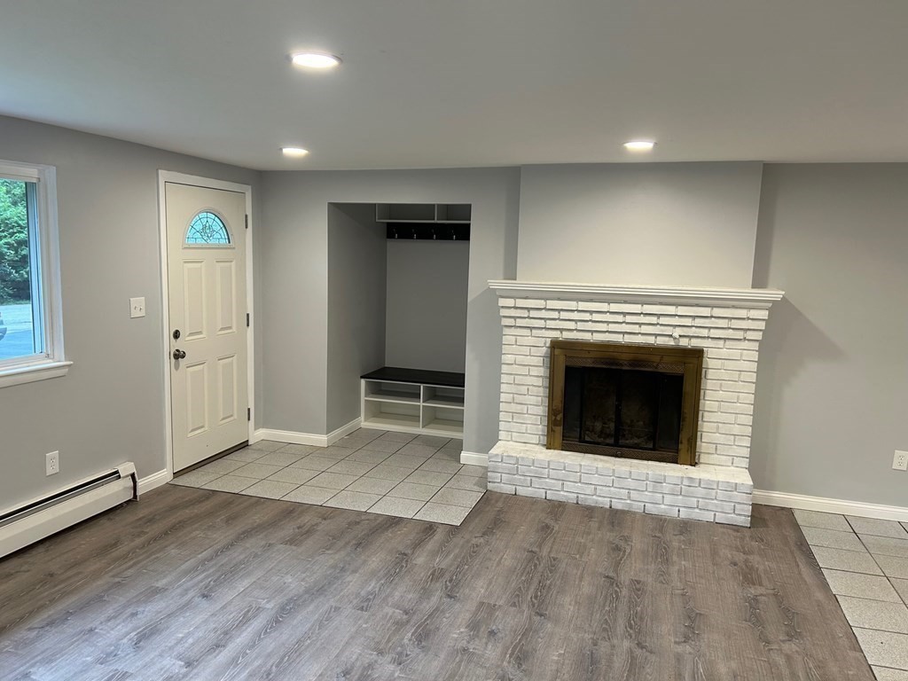 73 Brooks Street Maynard, MA 01754 - Photo 7 of 17 an empty room with wooden floor a fireplace and windows