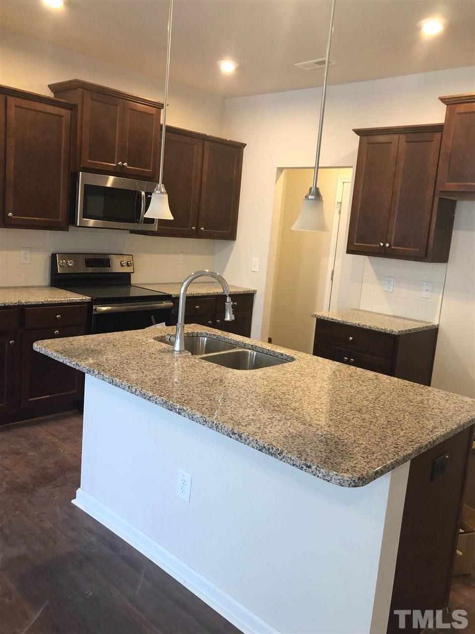 3627 Water Mist Lane, Unit 17 Raleigh, NC 27604 - Photo 6 of 17 a kitchen with stainless steel appliances granite countertop a sink a microwave a refrigerator and a stove