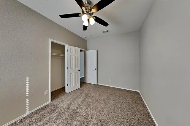 an empty room with chandelier fan