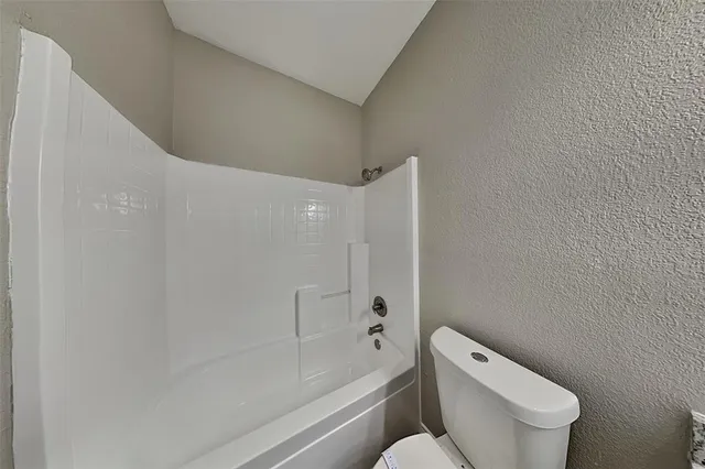 a white toilet sitting next to a bath tub