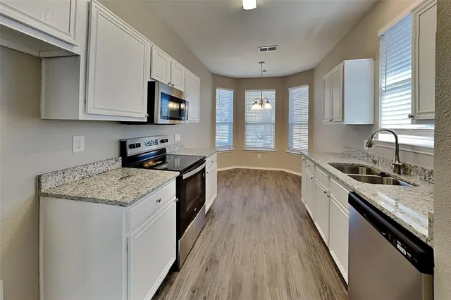 a kitchen with stainless steel appliances granite countertop wooden cabinets a stove a sink and a microwave