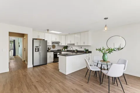 a kitchen with stainless steel appliances granite countertop a refrigerator a sink and white cabinets