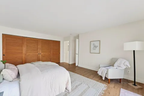 a dining room with wooden floor a chandelier fan a glass table and windows