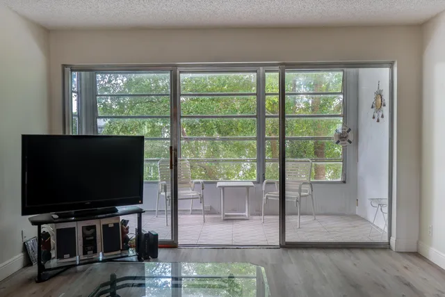 a living room with flat screen tv and floor to ceiling window