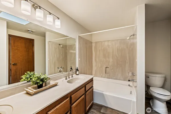 a bathroom with a granite countertop sink a toilet and shower