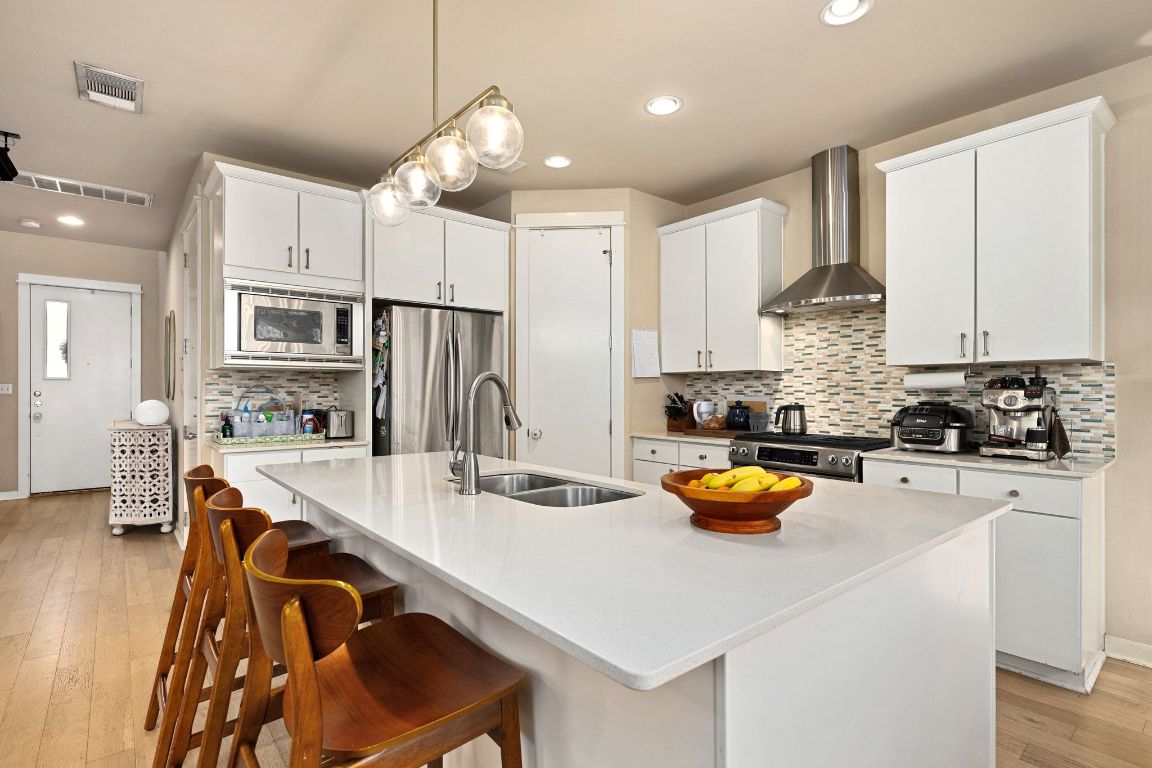 2819 Corbin Lane Austin, TX 78704 - Photo 2 of 22 a kitchen with a refrigerator a stove a sink dishwasher and white cabinets with wooden floor