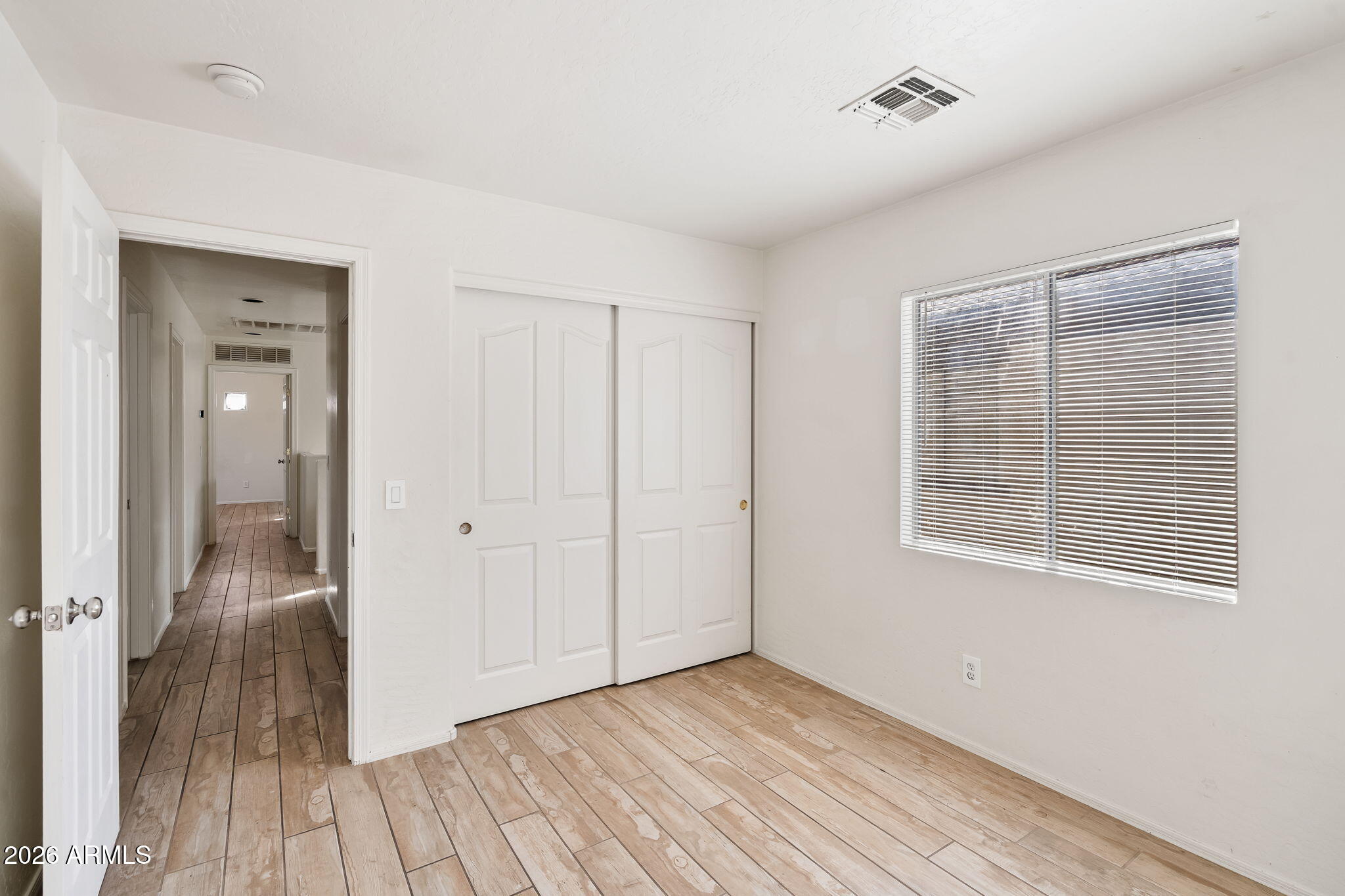 1332 East Dunbar Drive Phoenix, AZ 85042 - Photo 21 of 50 a view of an empty room with wooden floor and a window