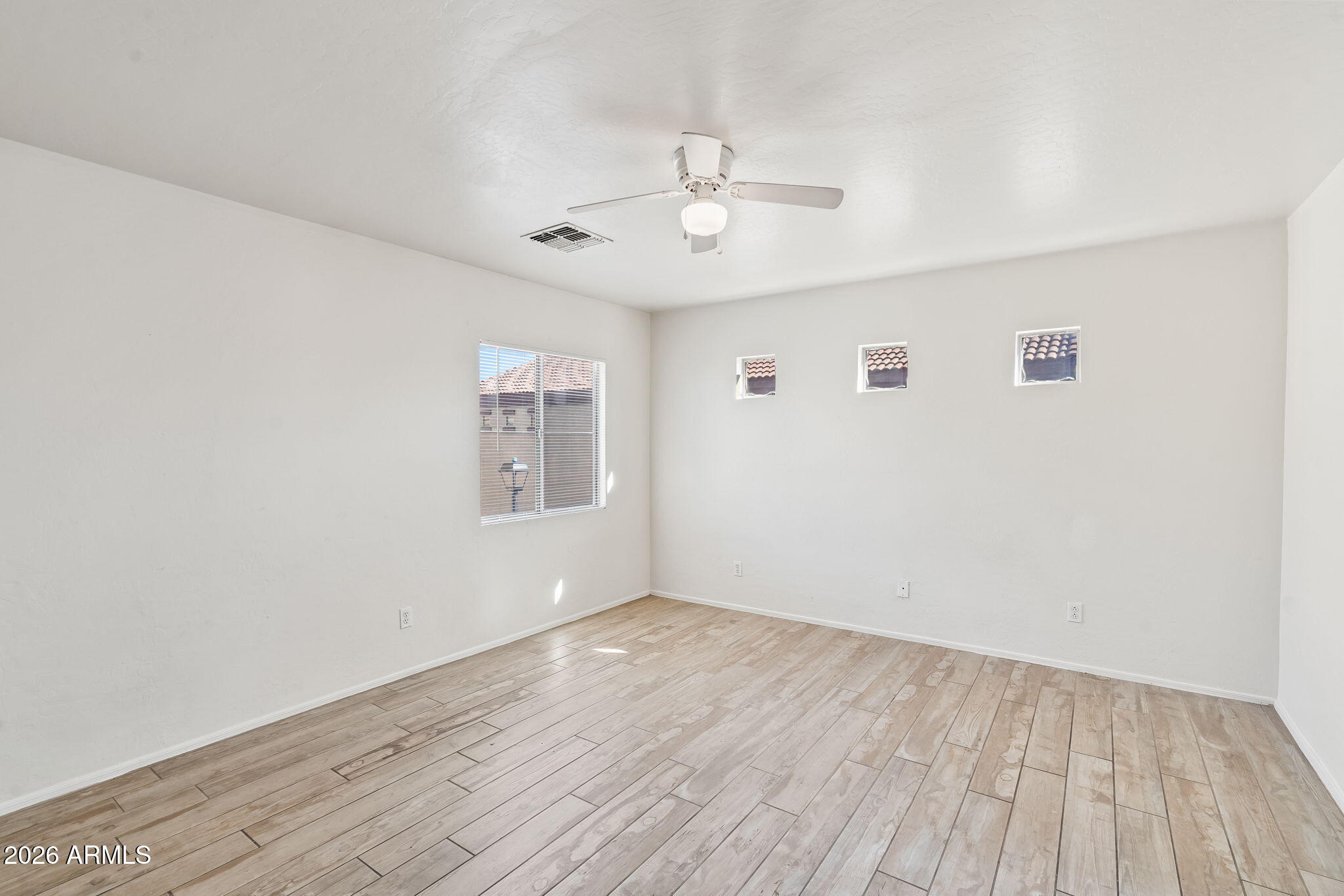 1332 East Dunbar Drive Phoenix, AZ 85042 - Photo 23 of 50 an empty room with wooden floor ceiling fan and windows
