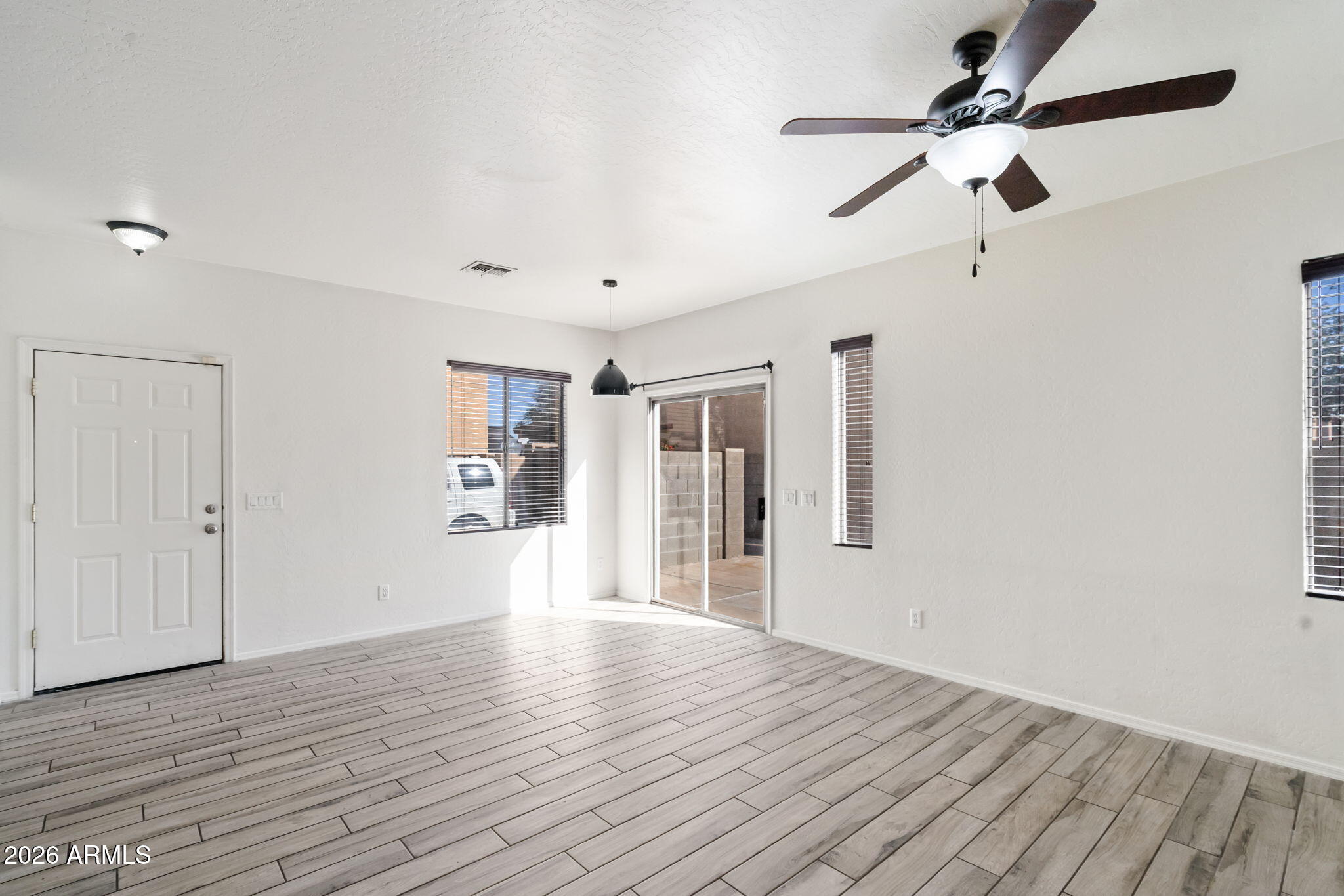 1332 East Dunbar Drive Phoenix, AZ 85042 - Photo 7 of 50 an empty room with wooden floor ceiling fan and windows