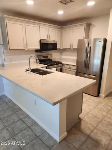 a kitchen with stainless steel appliances granite countertop a refrigerator stove top oven a sink and dishwasher