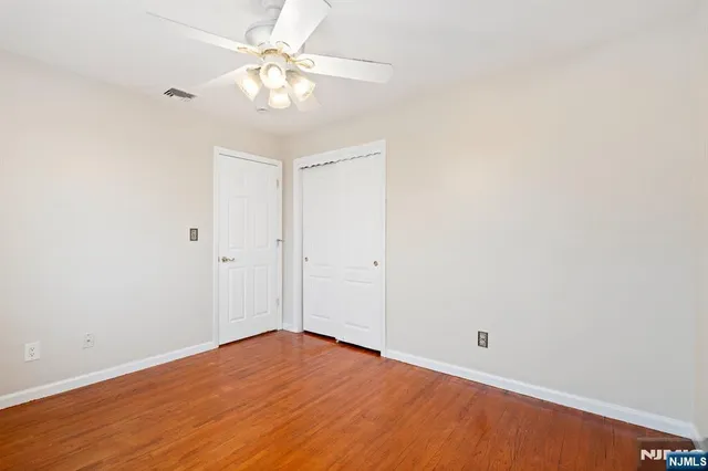 a view of a big room with wooden floor and a chandelier fan