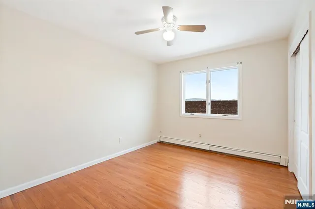 an empty room with wooden floor chandelier fan and windows