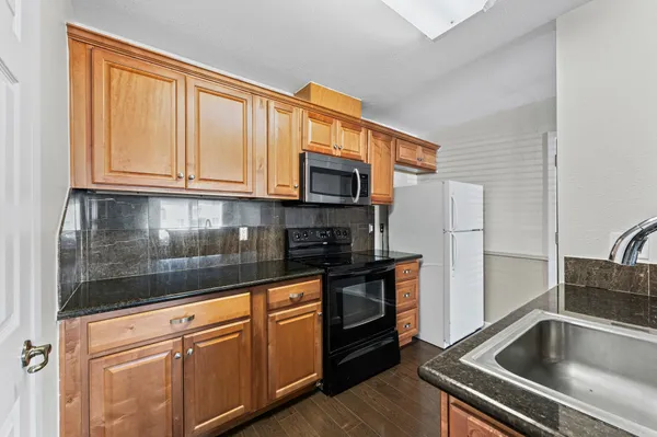 a kitchen with granite countertop a refrigerator stove and sink
