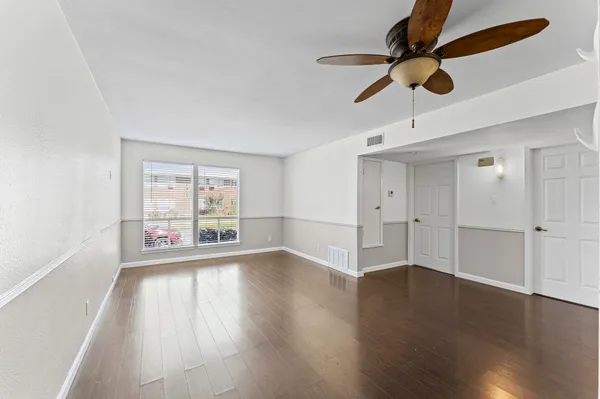 a view of an empty room with wooden floor and a window