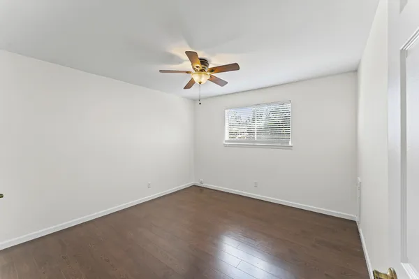 an empty room with wooden floor and a ceiling fan