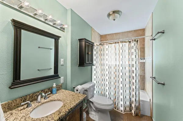 a bathroom with a granite countertop toilet a sink and a mirror