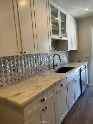 a kitchen with granite countertop white cabinets and sink