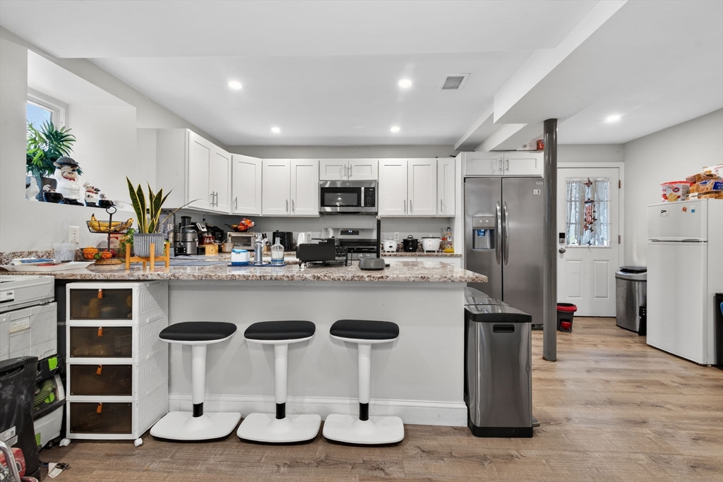 a kitchen with kitchen island granite countertop a refrigerator and a sink