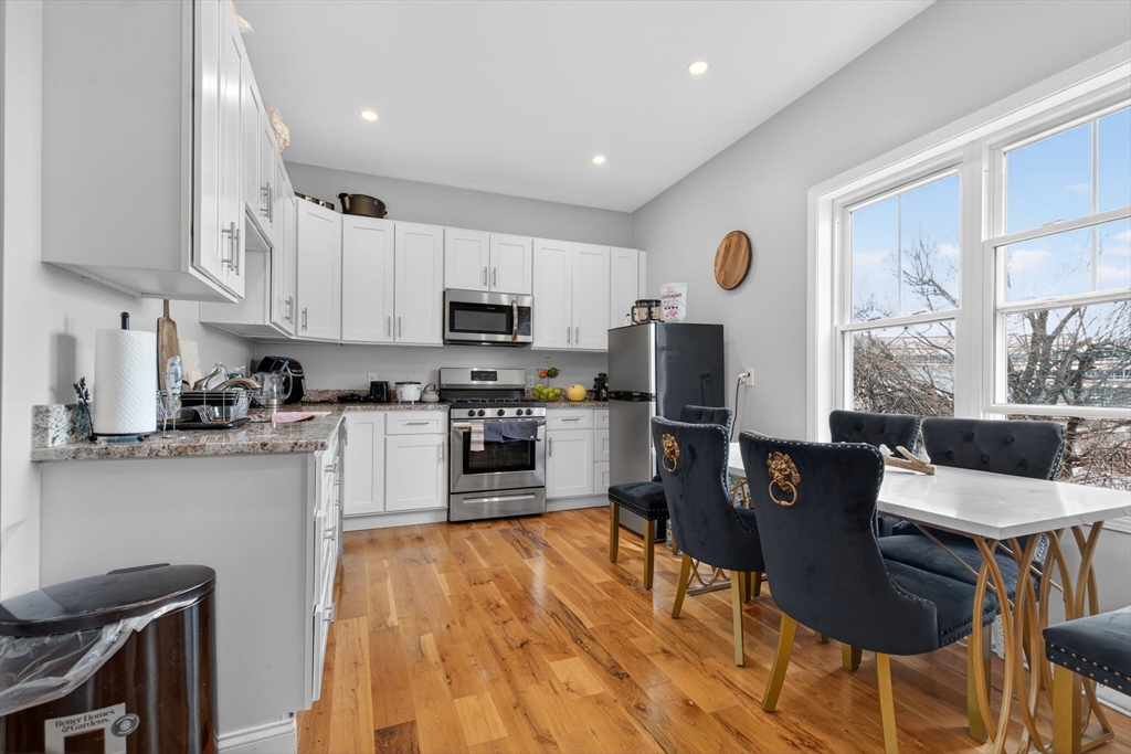 1684 North Shore Road Revere, MA 02151 - Photo 25 of 39 a open kitchen with stainless steel appliances granite countertop a stove top oven a sink dishwasher a dining table and chairs with wooden floor