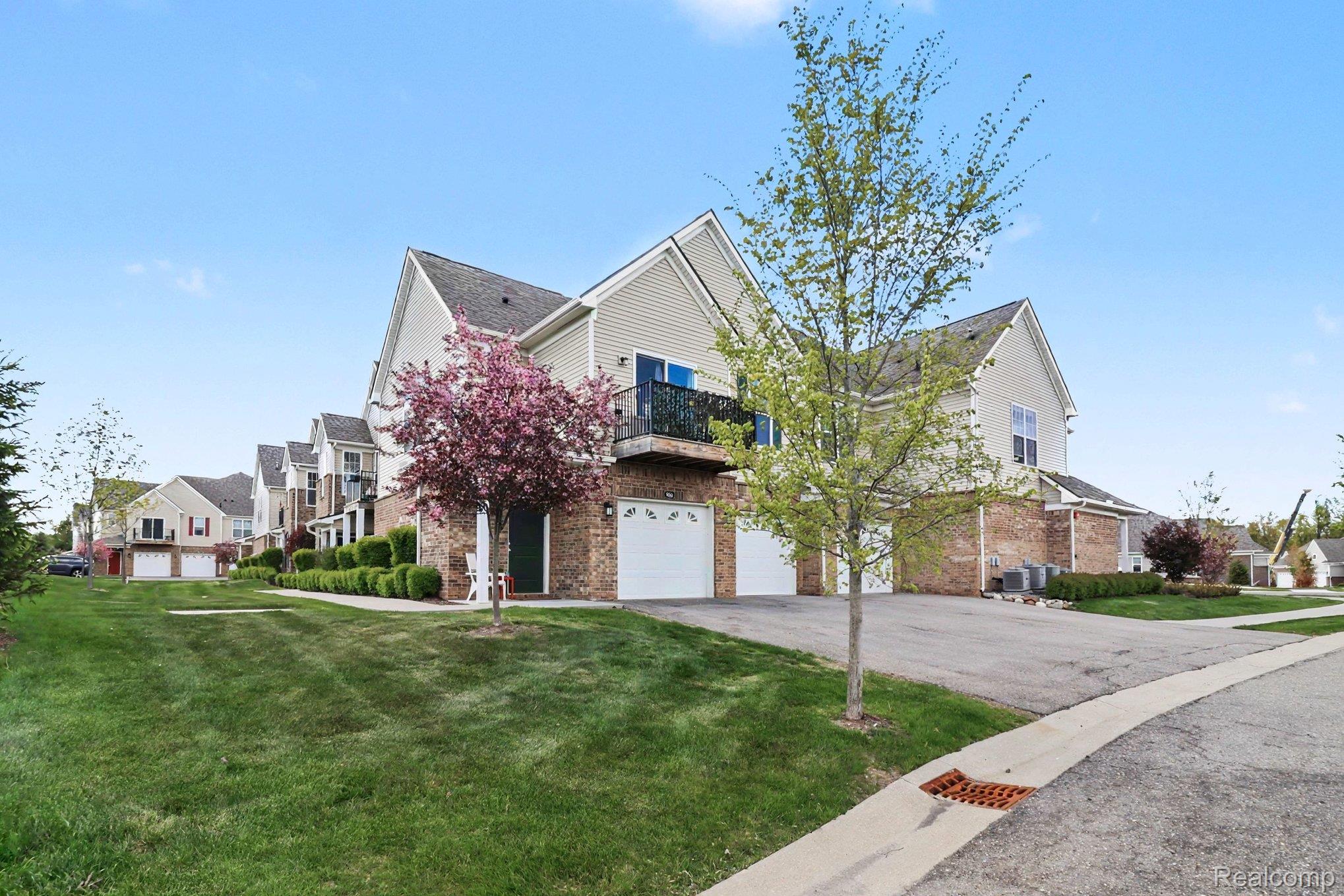 9864 Ridge Run Street Howell, MI 48855 - Photo 2 of 23 Traditional-style home featuring a residential view, an attached garage, driveway, and a balcony