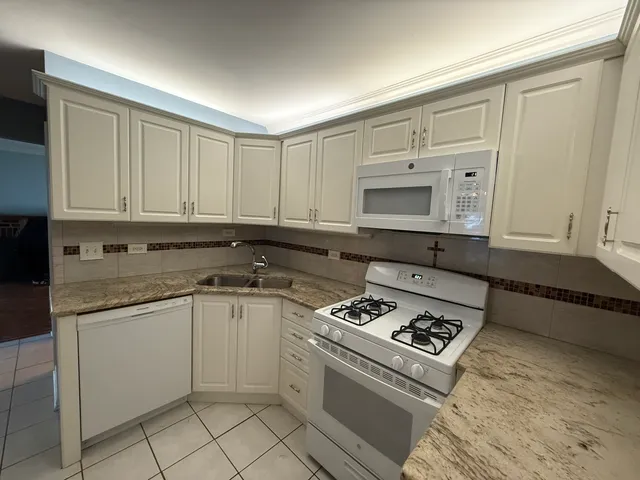 a kitchen with granite countertop a stove sink and cabinets