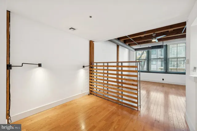 a view of an empty room with a window and wooden floor