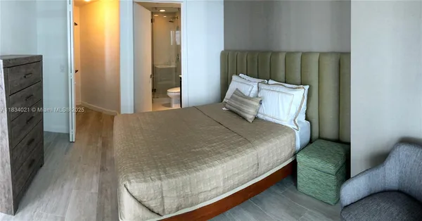 a large bed sitting in a bedroom next to a window and a wooden floor