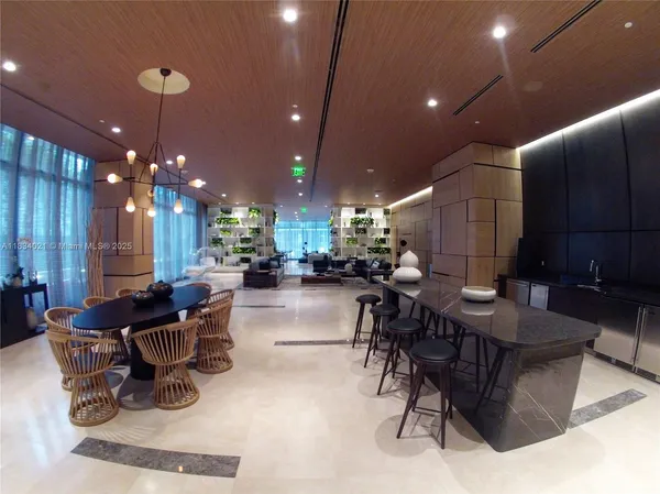 a room with lots of tables a chandelier and kitchen view