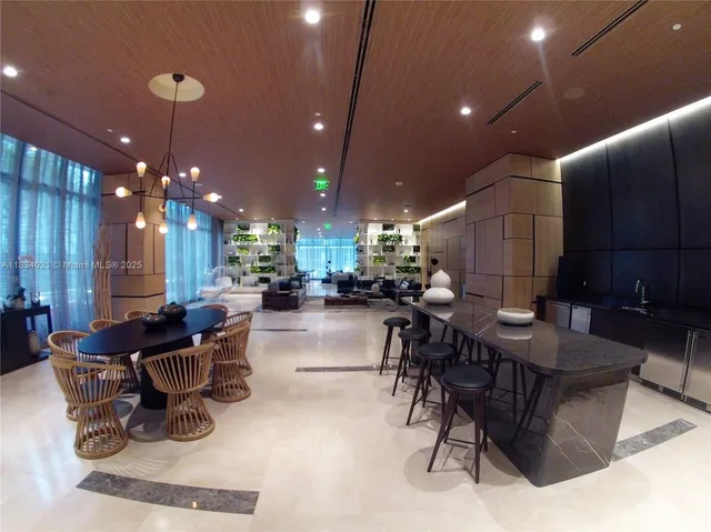 a room with lots of tables a chandelier and kitchen view