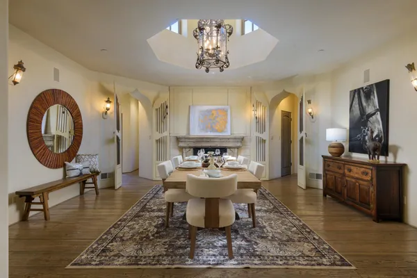 a living room with dining table a mirror and a chandelier