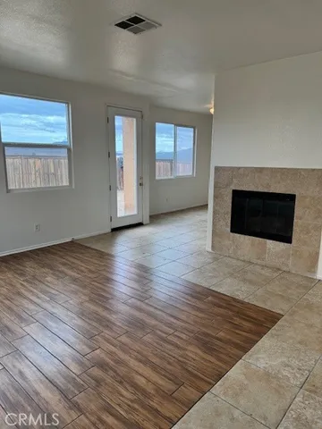 an empty room with wooden floor fireplace and windows