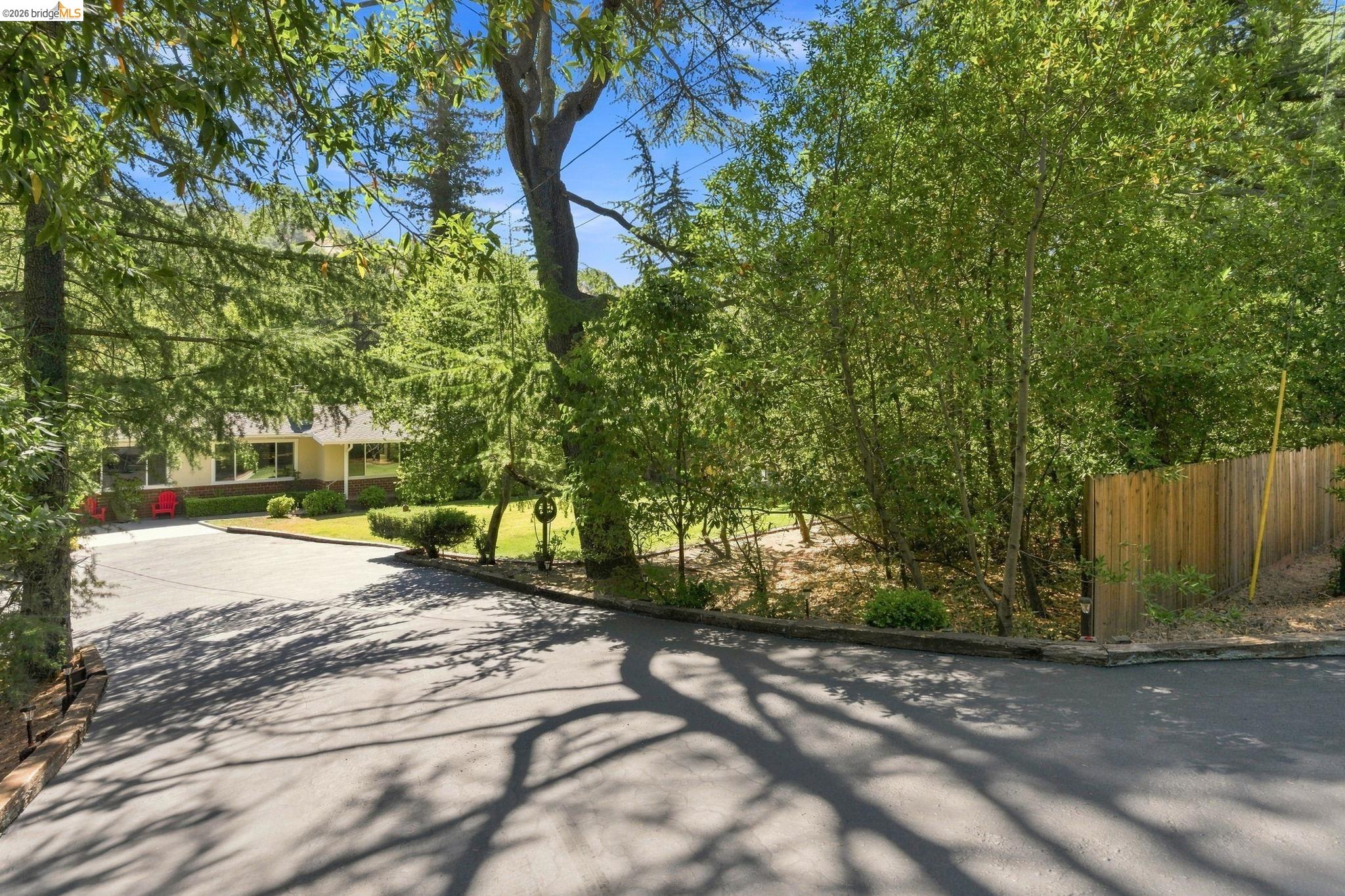 5075 Alhambra Valley Road Martinez, CA 94553 - Photo 53 of 68 Paved driveway leading to a residence with a covered front porch, surrounded by mature trees and a manicured lawn
