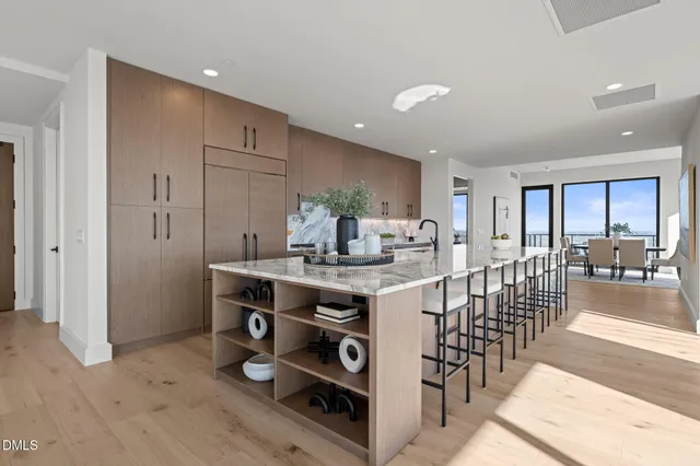 a kitchen with stainless steel appliances kitchen island granite countertop a table chairs sink and cabinets