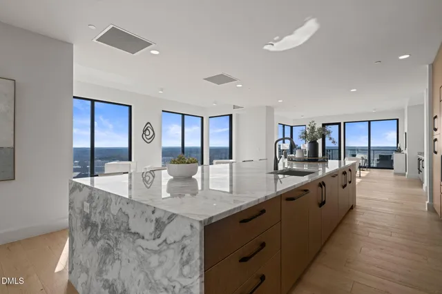 a large white kitchen with kitchen island a island a sink a stove and a refrigerator