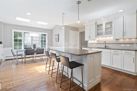 a open kitchen with granite countertop a stove a sink a dining table and chairs with wooden floor