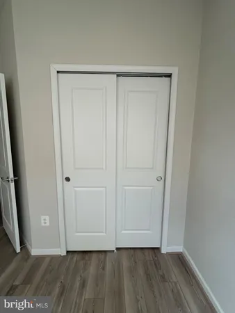 a view of an empty room with wooden floor and closet