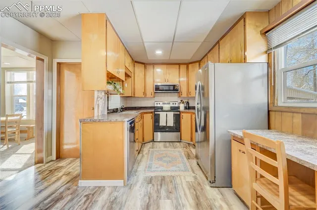 a kitchen with stainless steel appliances granite countertop a refrigerator a oven a sink with island and wooden cabinets