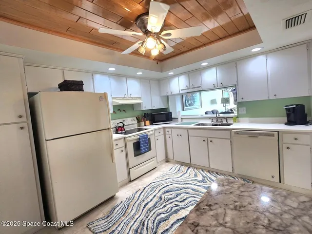 a kitchen with a sink white cabinets and white appliances