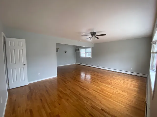 a view of empty room with a window and wooden floor